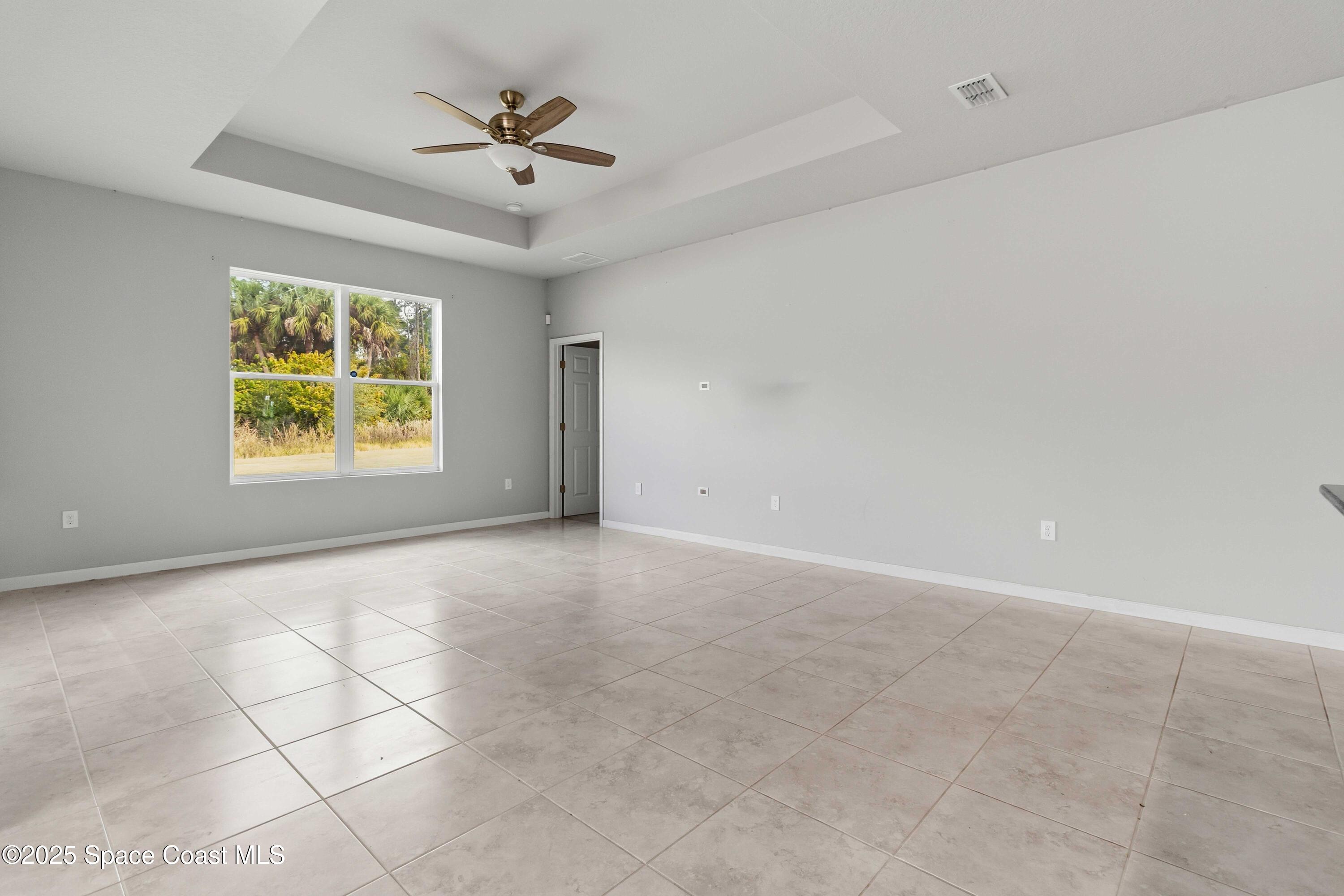 988 Corbin Circle Southwest Palm Bay, FL 32908 - Photo 8 of 26 an empty room with windows and chandelier fan