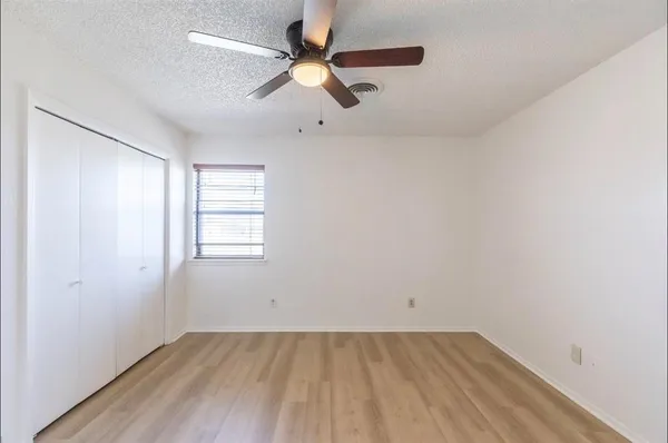 an empty room with a window and a ceiling fan