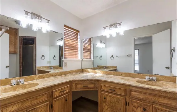 a bathroom with a granite countertop double vanity sink and a mirror