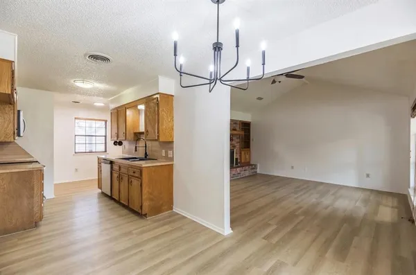 a view of a kitchen with wooden floor a sink a refrigerator and cabinets