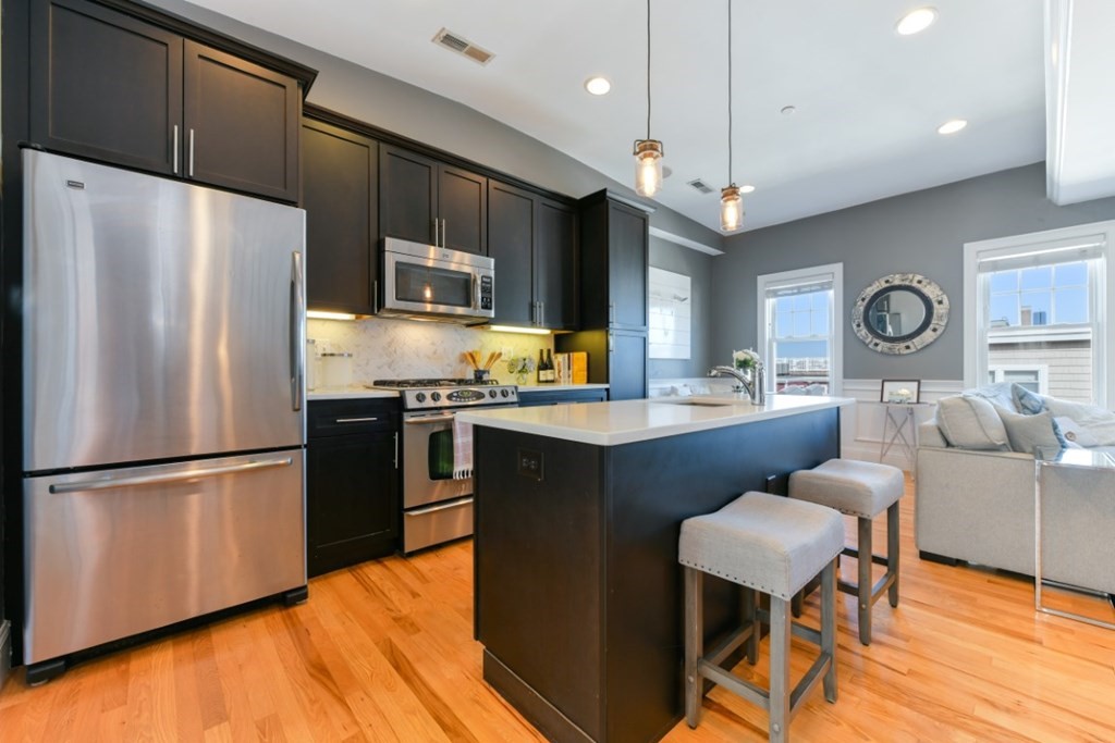 5 Grimes Street, Unit 3 Boston, MA 02127 - Photo 5 of 16 a kitchen with stainless steel appliances granite countertop a refrigerator a stove a sink dishwasher a dining table and chairs with wooden floor