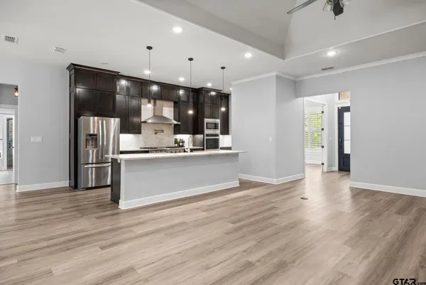 a view of a livingroom with a flat screen tv wooden floor and a ceiling fan