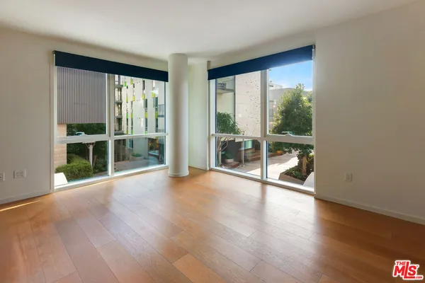 a view of empty room with wooden floor and floor to ceiling window