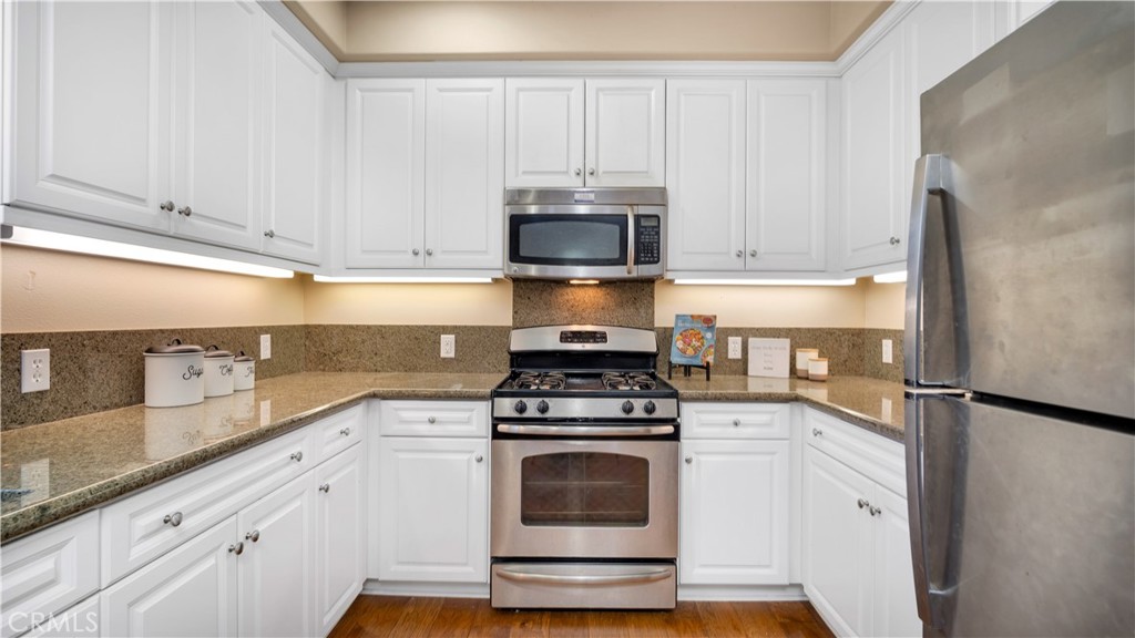 66 Full Moon Irvine, CA 92618 - Photo 15 of 32 a kitchen with granite countertop white cabinets and white stainless steel appliances