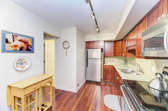 a room with stainless steel appliances a stove a refrigerator and a wooden floors