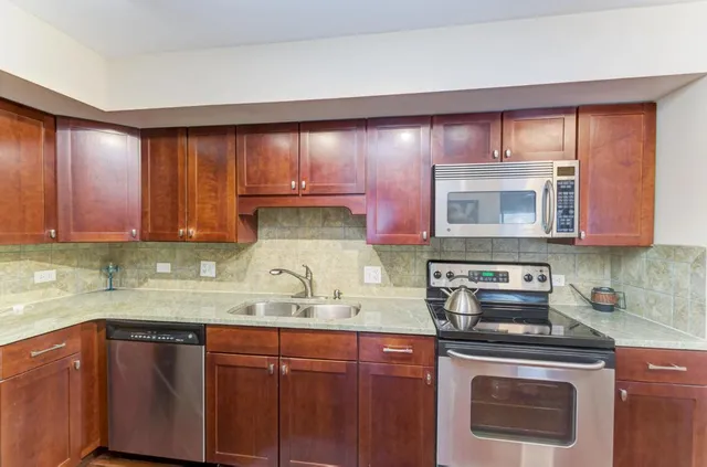 a kitchen with stainless steel appliances granite countertop wooden cabinets and a stove top oven