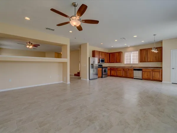 an empty room with a kitchen and a ceiling fan