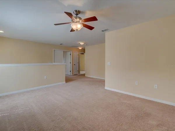 an empty room with chandelier fan and outdoor space