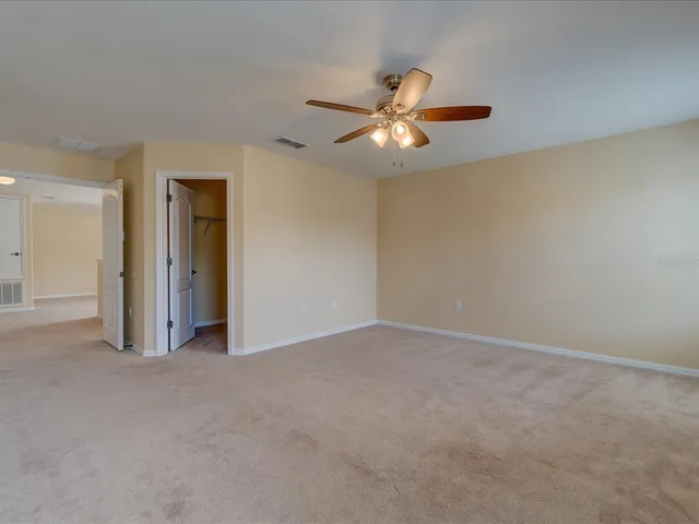 an empty room with closet and a chandelier fan