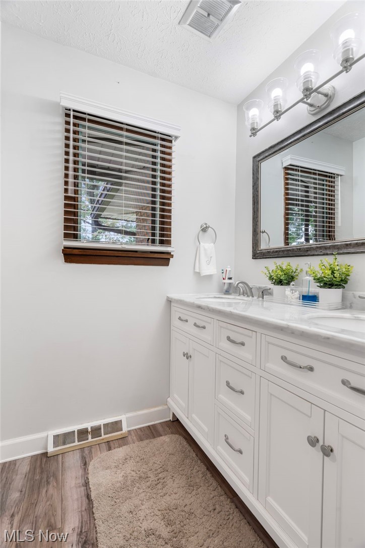 5722 Wiclif Road Northeast Canton, OH 44721 - Photo 22 of 35 Bathroom with hardwood flooring, mirror, dual large bowl vanity, and a textured ceiling
