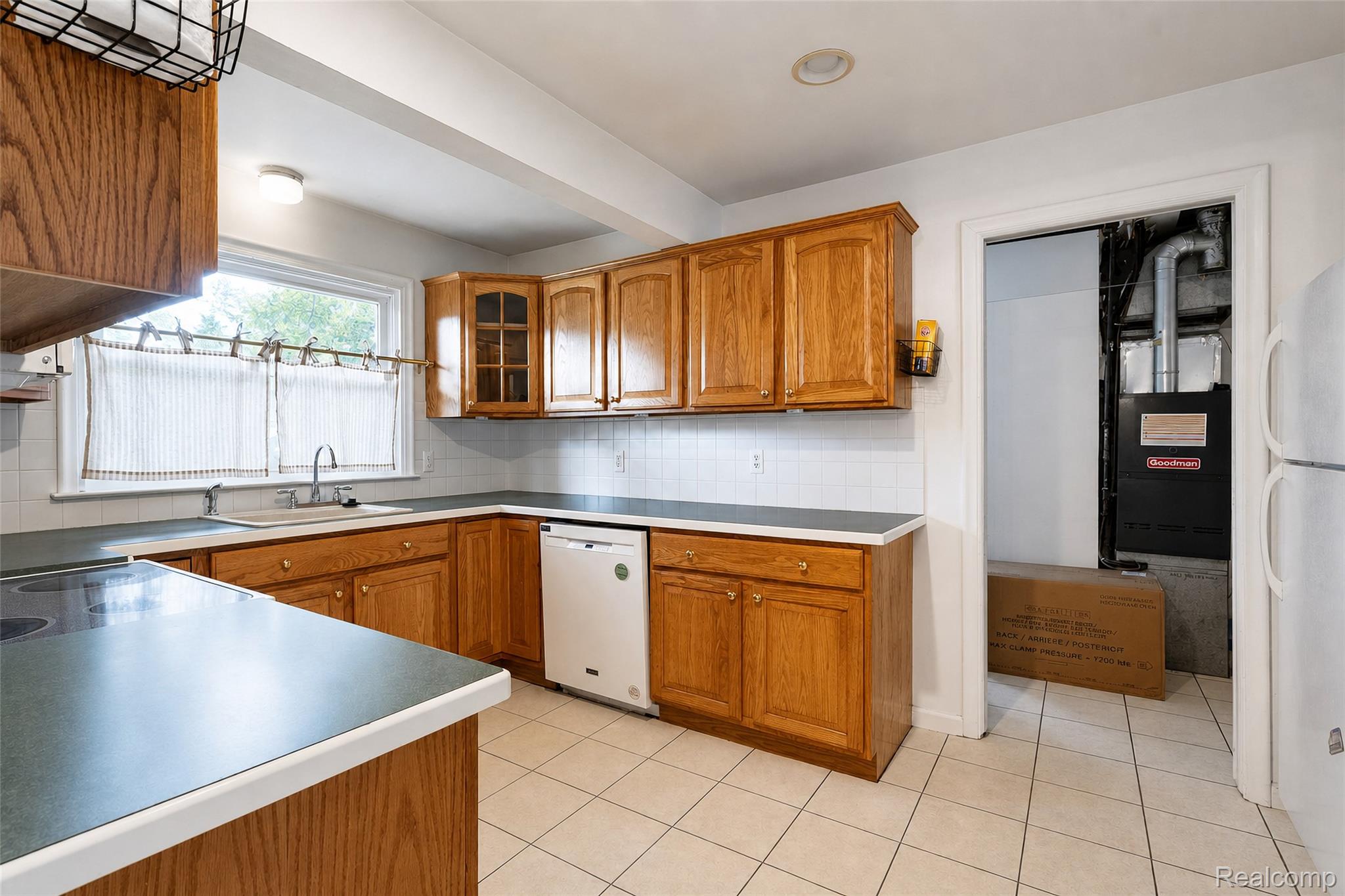 1846 Pembroke Road Birmingham, MI 48009 - Photo 21 of 37 Wood cabinetry with gold-tone hardware, white tile backsplash, corner sink, white appliances, and tiled flooring