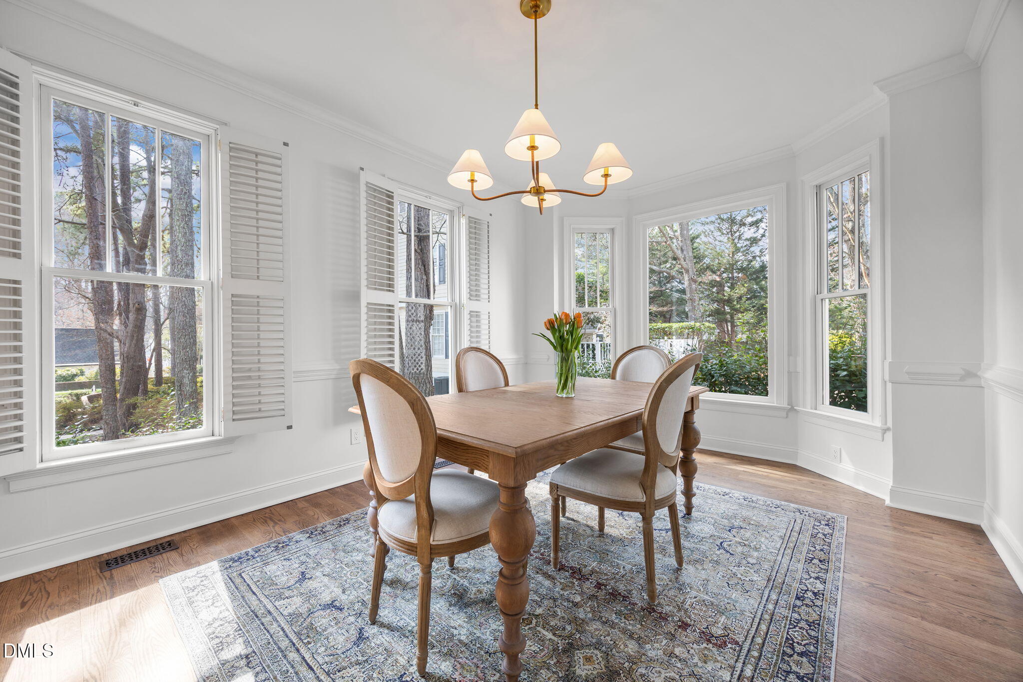 8805 Mourning Dove Road Raleigh, NC 27615 - Photo 12 of 55 a dining room with wooden floor a chandelier a wooden table and chairs