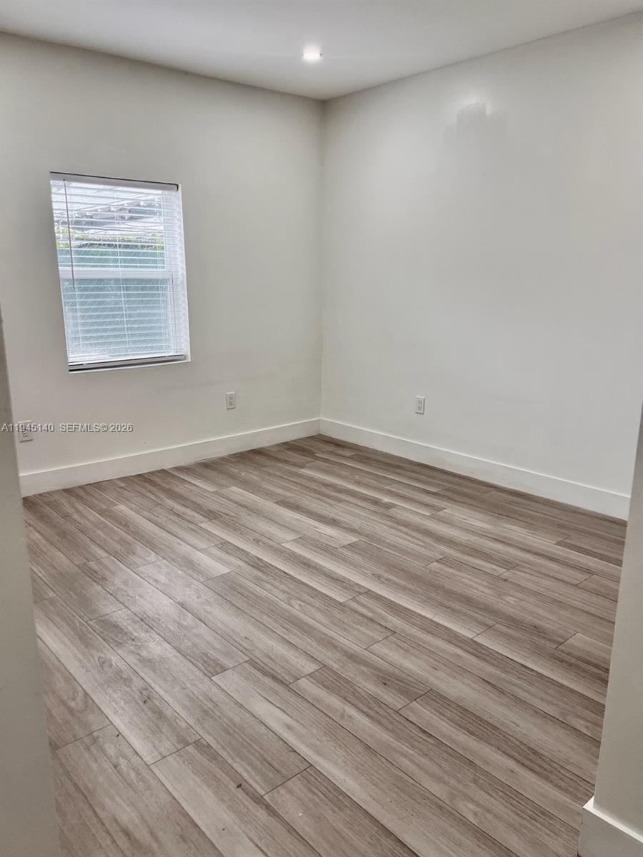 852 Southwest 13th Avenue, Unit 3 Miami, FL 33135 - Photo 12 of 20 a view of an empty room with wooden floor and a window