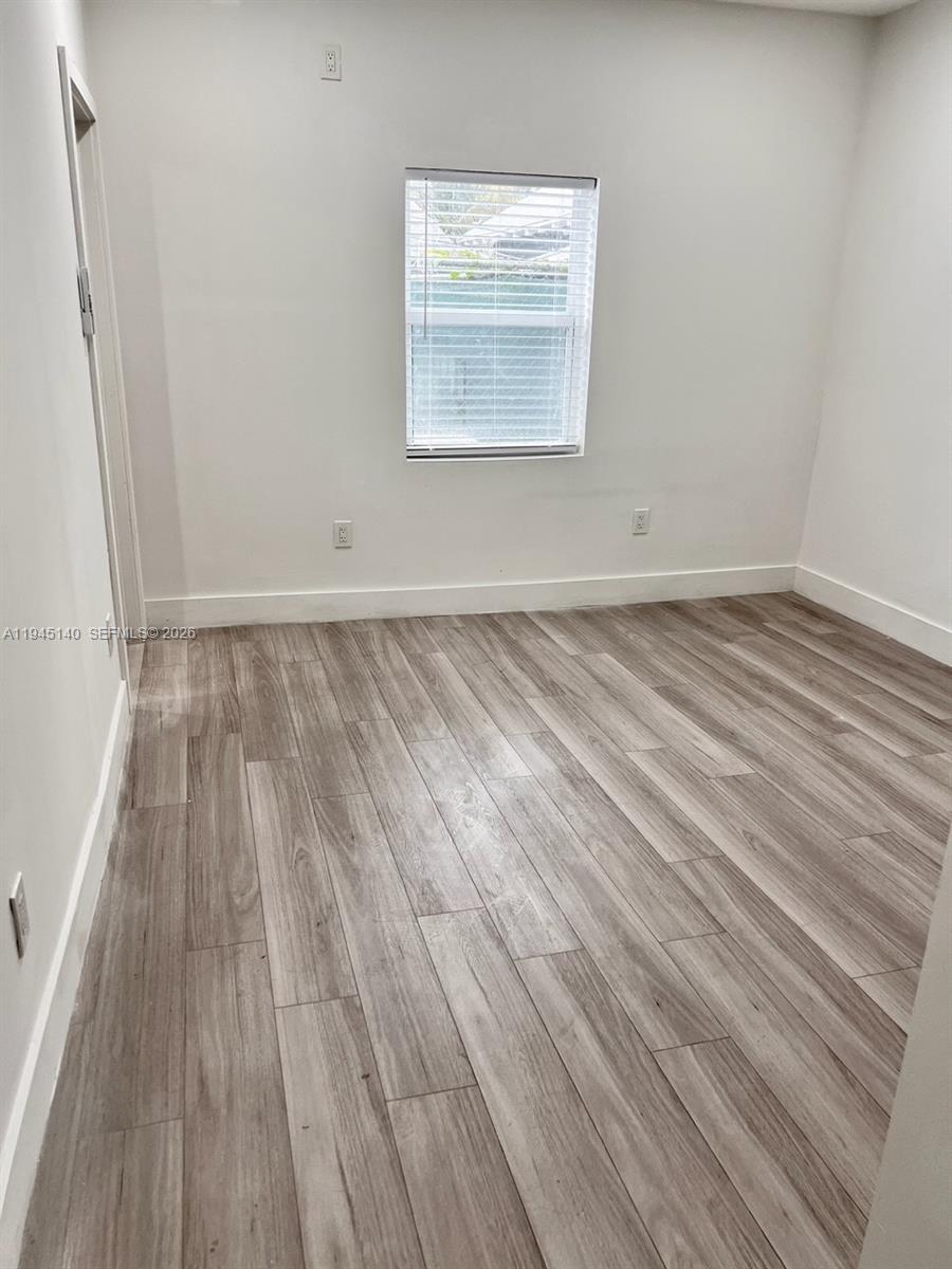 852 Southwest 13th Avenue, Unit 3 Miami, FL 33135 - Photo 15 of 20 a view of a room with wooden floor and white walls