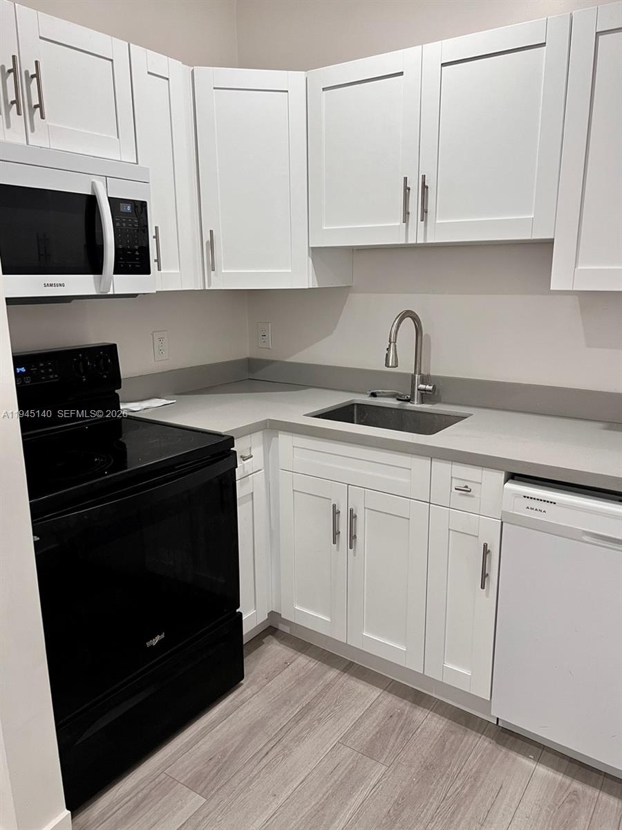 852 Southwest 13th Avenue, Unit 3 Miami, FL 33135 - Photo 7 of 20 a kitchen with granite countertop white cabinets and black appliances