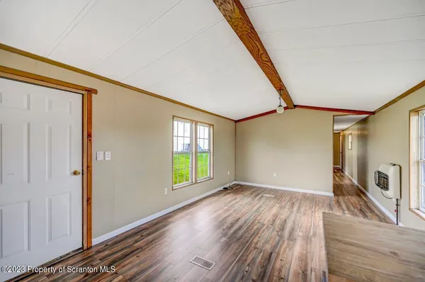 a view of an empty room with a window and wooden floor