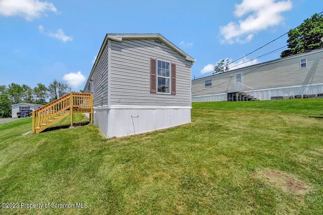 a view of a tiny house with a big yard and large tree