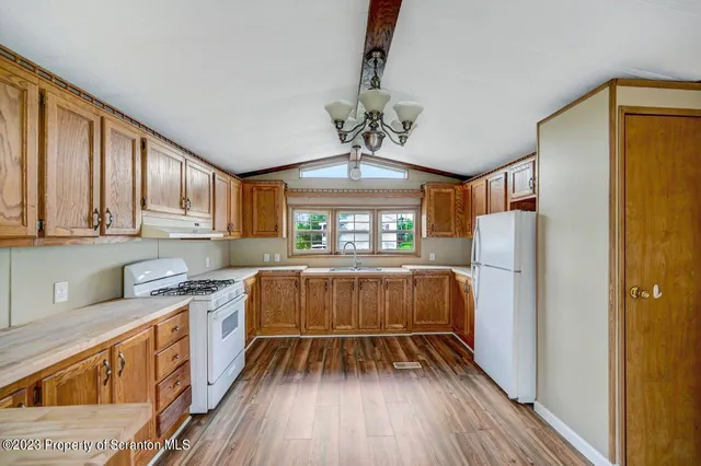 a kitchen with a refrigerator wooden floor and window