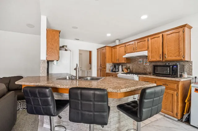 a kitchen with stainless steel appliances granite countertop a table chairs and a refrigerator