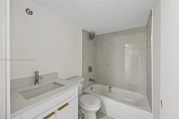 a bathroom with a granite countertop sink a toilet and shower