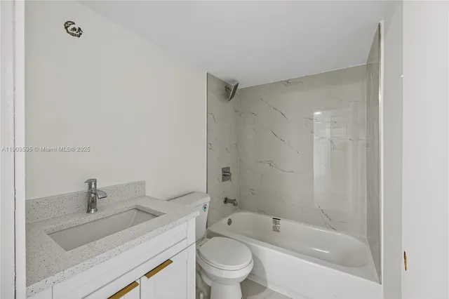 a bathroom with a granite countertop sink a toilet and shower