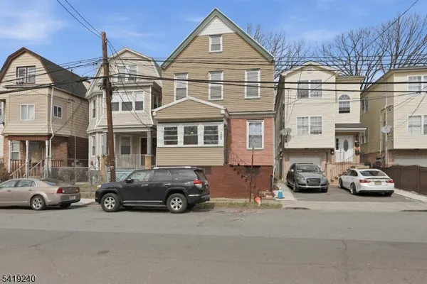 a front view of a residential apartment building with cars parked