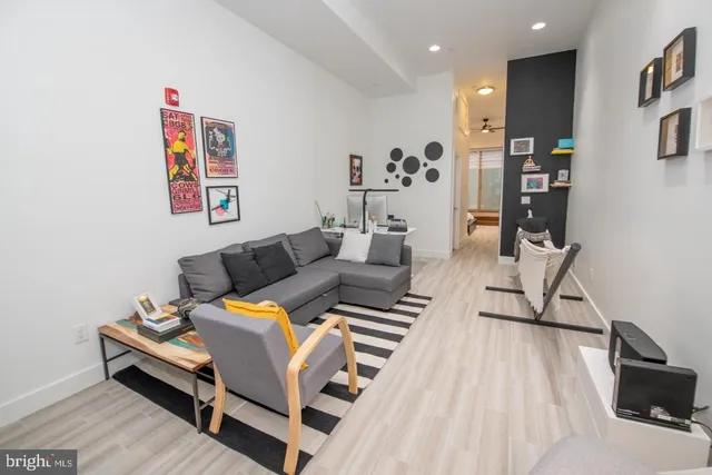 a living room with furniture a wooden floor and next to a window