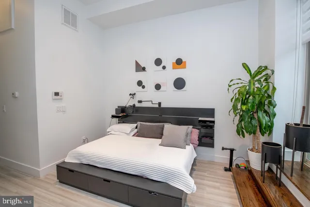 a bedroom with a bed and a potted plant with wooden floor