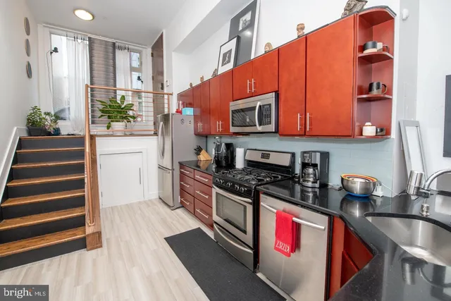 a kitchen with stainless steel appliances granite countertop a stove a sink and a microwave