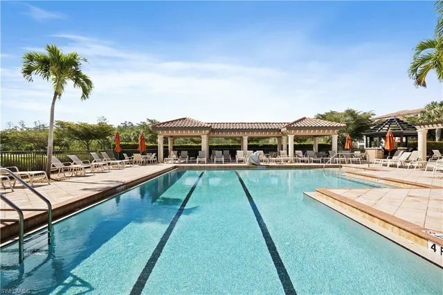 a view of swimming pool with a yard and palm trees