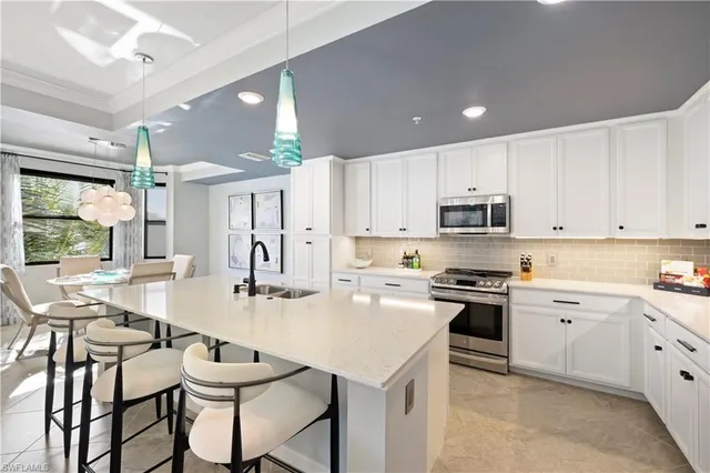 a kitchen with kitchen island granite countertop a table chairs sink and cabinets