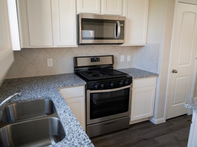 2533 Sturgeon Way Conroe, TX 77384 - Photo 4 of 30 a kitchen with white cabinets and black appliances