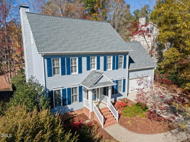 a aerial view of a house with yard and trees in the background