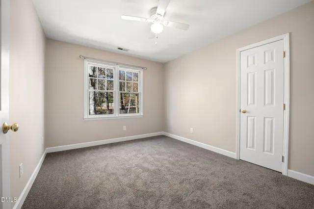 a view of an empty room with a window and a ceiling fan