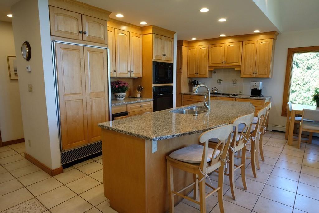 69 Piney Point Road Marion, MA 02738 - Photo 7 of 16 a kitchen with kitchen island granite countertop wooden cabinets and refrigerator