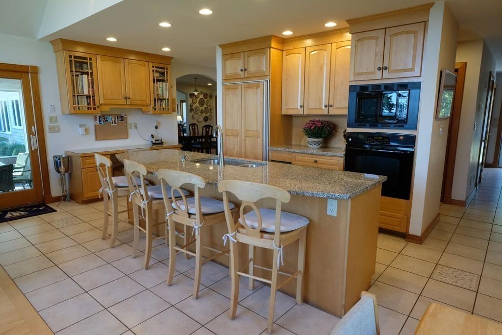 69 Piney Point Road Marion, MA 02738 - Photo 8 of 16 a kitchen with stainless steel appliances kitchen island granite countertop a table chairs and a refrigerator