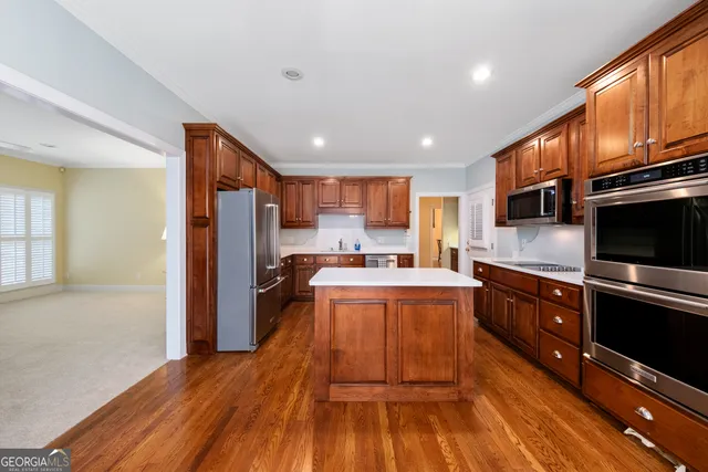 a kitchen with stainless steel appliances granite countertop a refrigerator a stove top oven a sink dishwasher and wooden cabinets with wooden floor