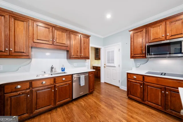 a kitchen with stainless steel appliances granite countertop wooden cabinets a sink and dishwasher a stove top oven with wooden floor