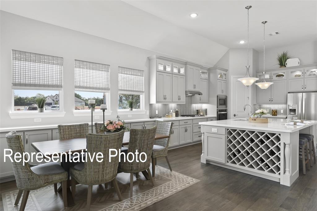 331 Fire Blade Drive Aledo, TX 76008 - Photo 5 of 17 Open-concept kitchen featuring wood-finish flooring, light gray cabinetry, stainless steel appliances, a center island with built-in wine storage, and recessed lighting