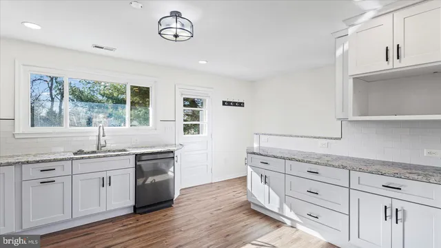 a kitchen with granite countertop a sink a window stainless steel appliances and cabinets