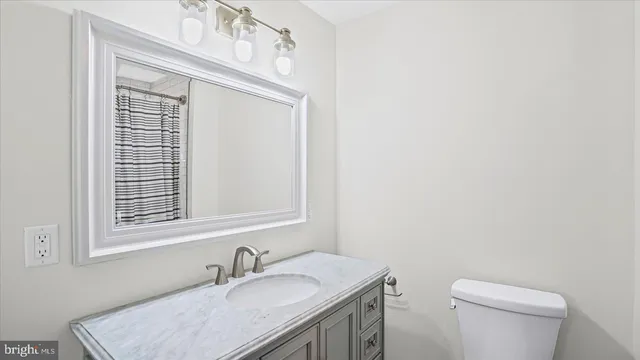 a bathroom with a sink vanity granite toilet and a mirror