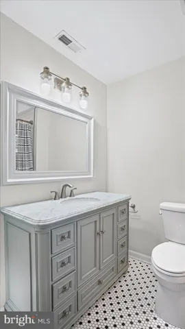 a bathroom with a granite countertop sink vanity mirror and toilet