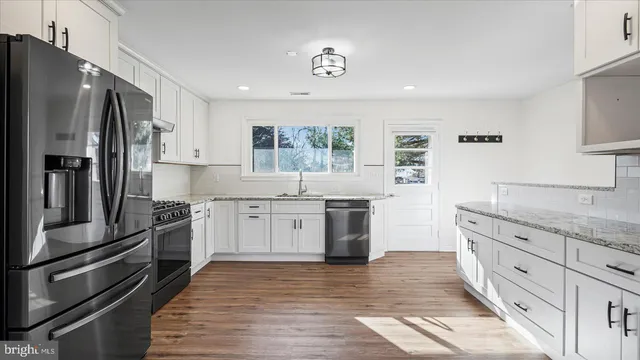 a kitchen with granite countertop a refrigerator stove and sink