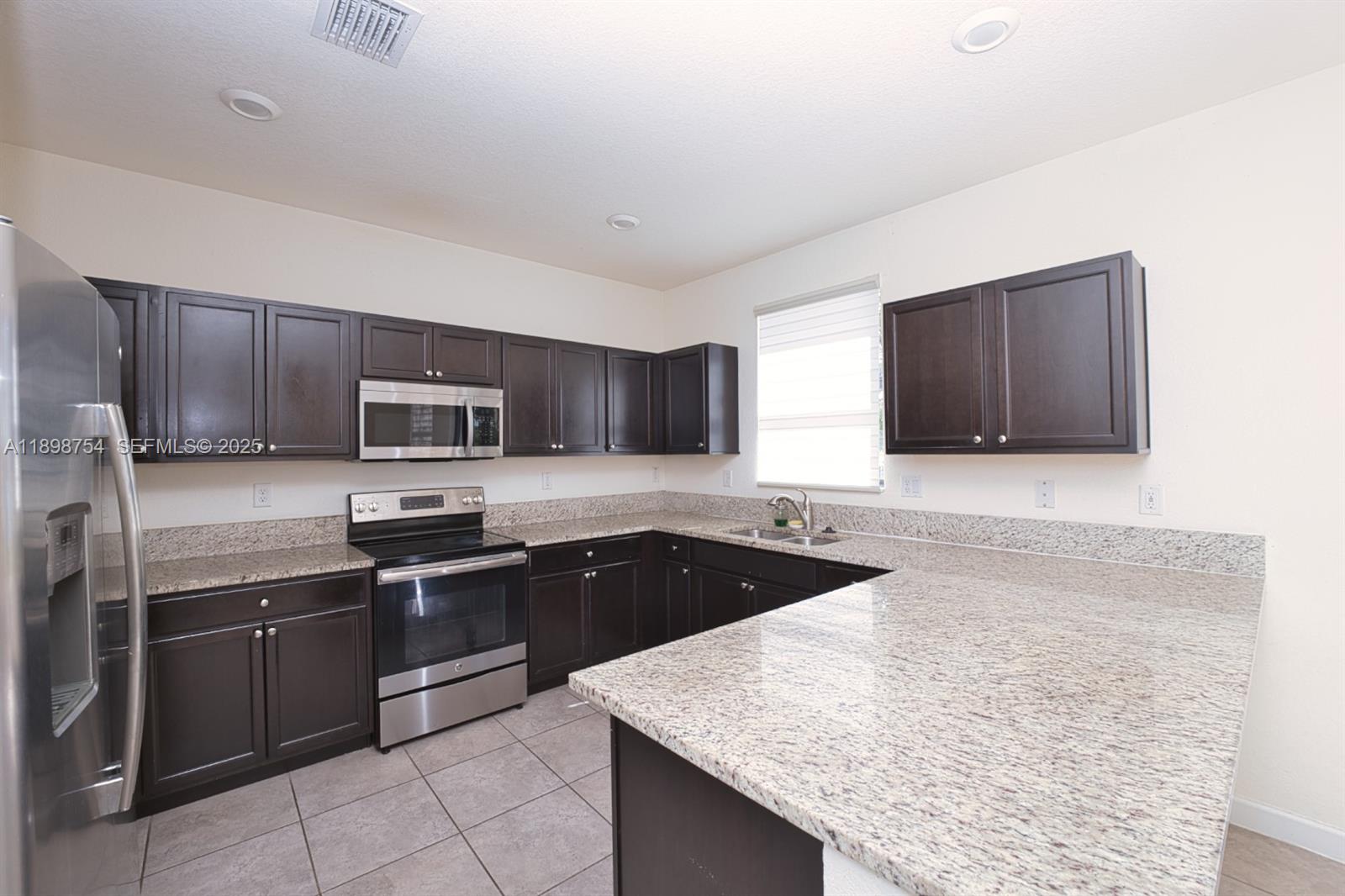 3412 West 103rd Terrace Hialeah, FL 33018 - Photo 12 of 44 a kitchen with stainless steel appliances granite countertop a sink stove and microwave