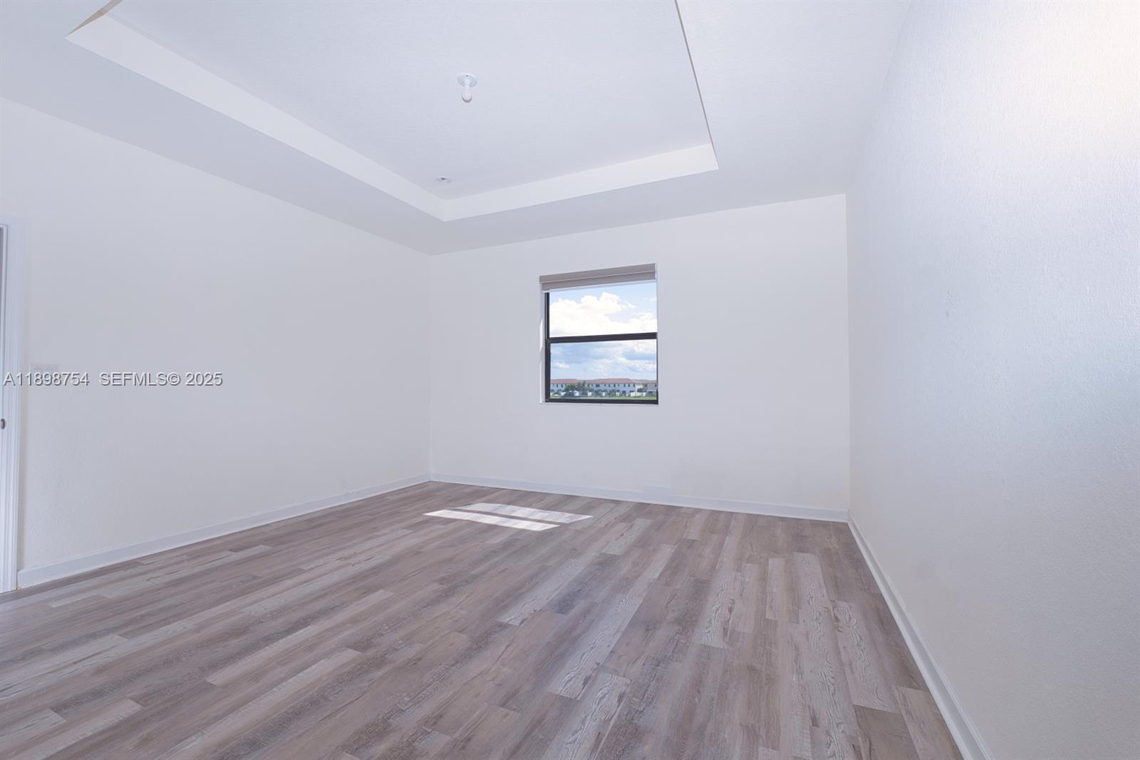 3412 West 103rd Terrace Hialeah, FL 33018 - Photo 21 of 44 an empty room with wooden floor and windows
