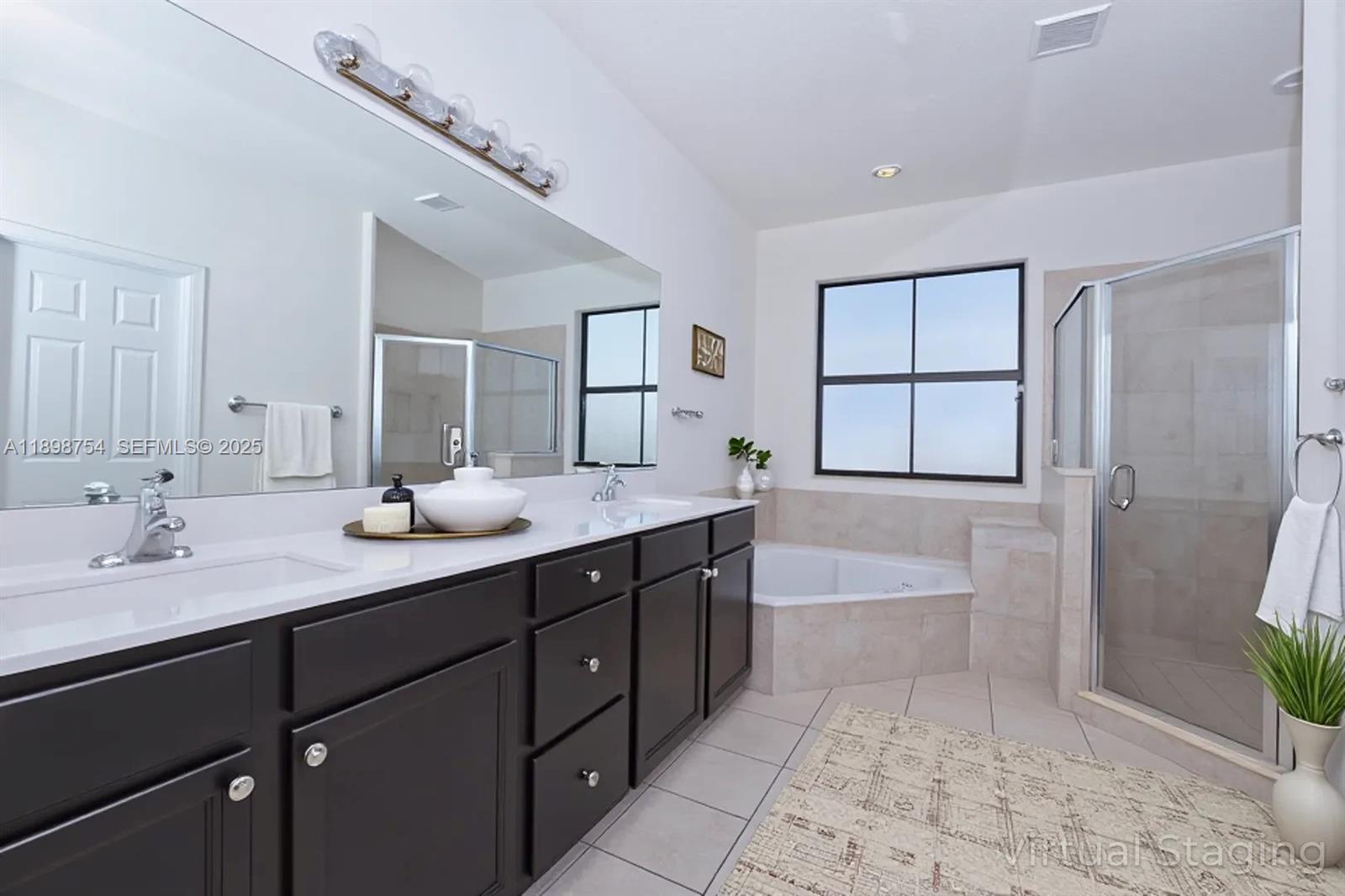 3412 West 103rd Terrace Hialeah, FL 33018 - Photo 23 of 44 a spacious bathroom with a double vanity sink a large mirror and a bathtub