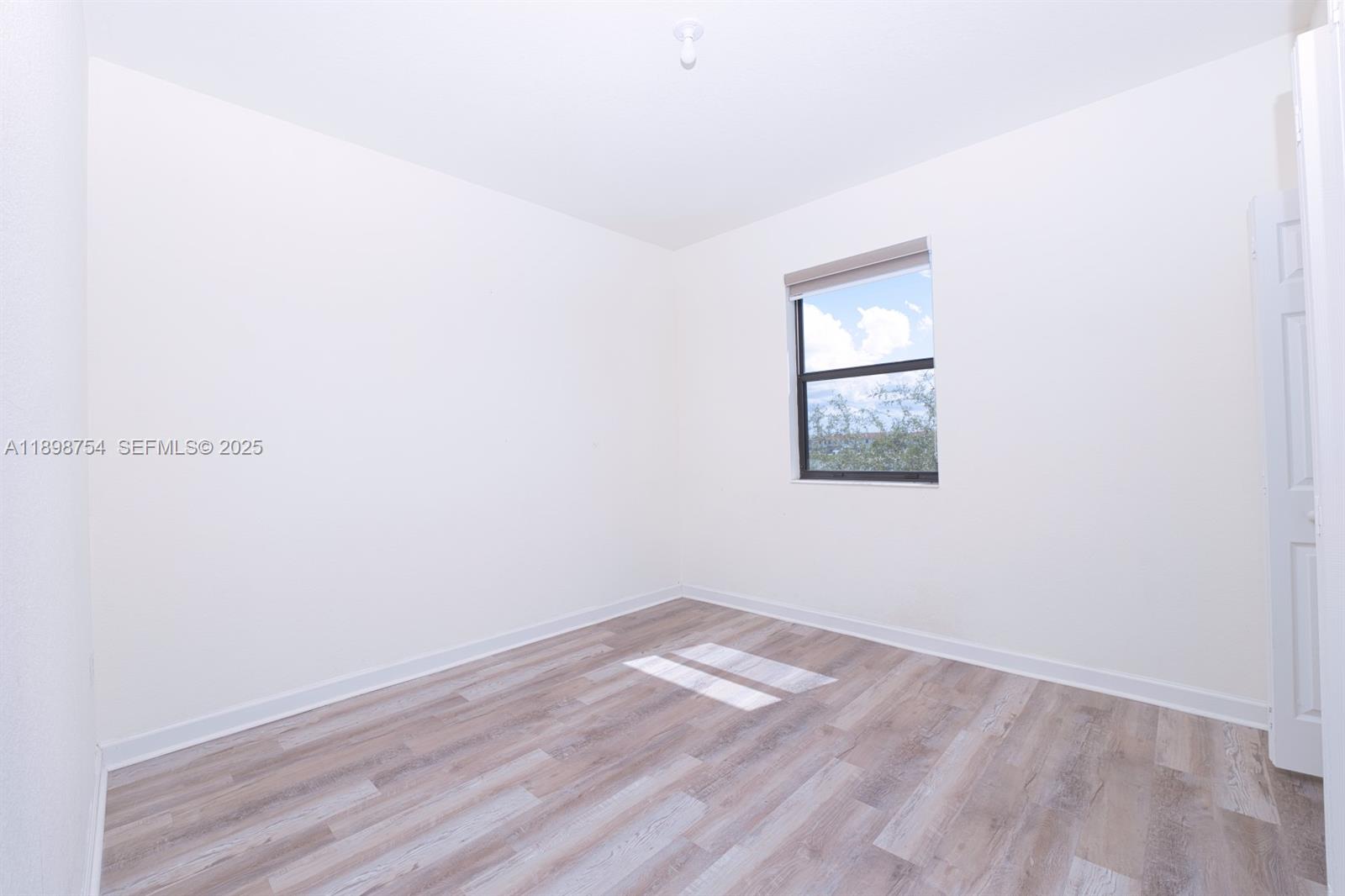 3412 West 103rd Terrace Hialeah, FL 33018 - Photo 31 of 44 an empty room with wooden floor and windows