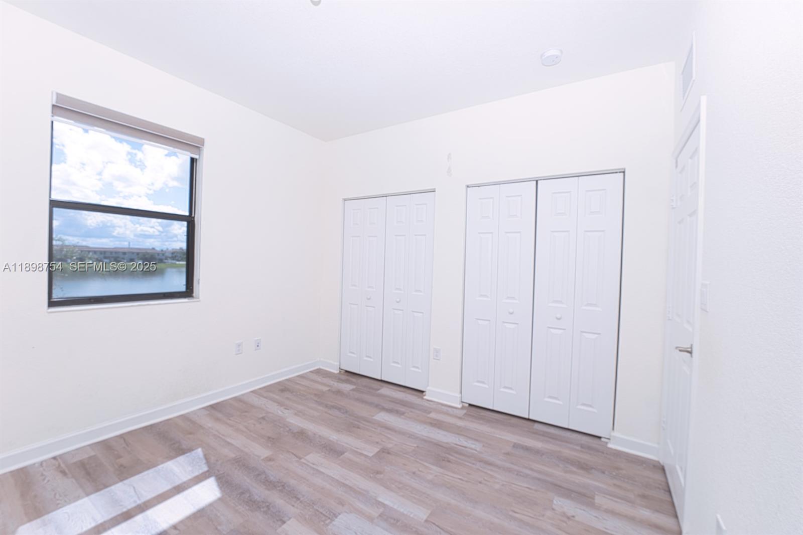 3412 West 103rd Terrace Hialeah, FL 33018 - Photo 32 of 44 a view of an empty room with wooden floor and a window