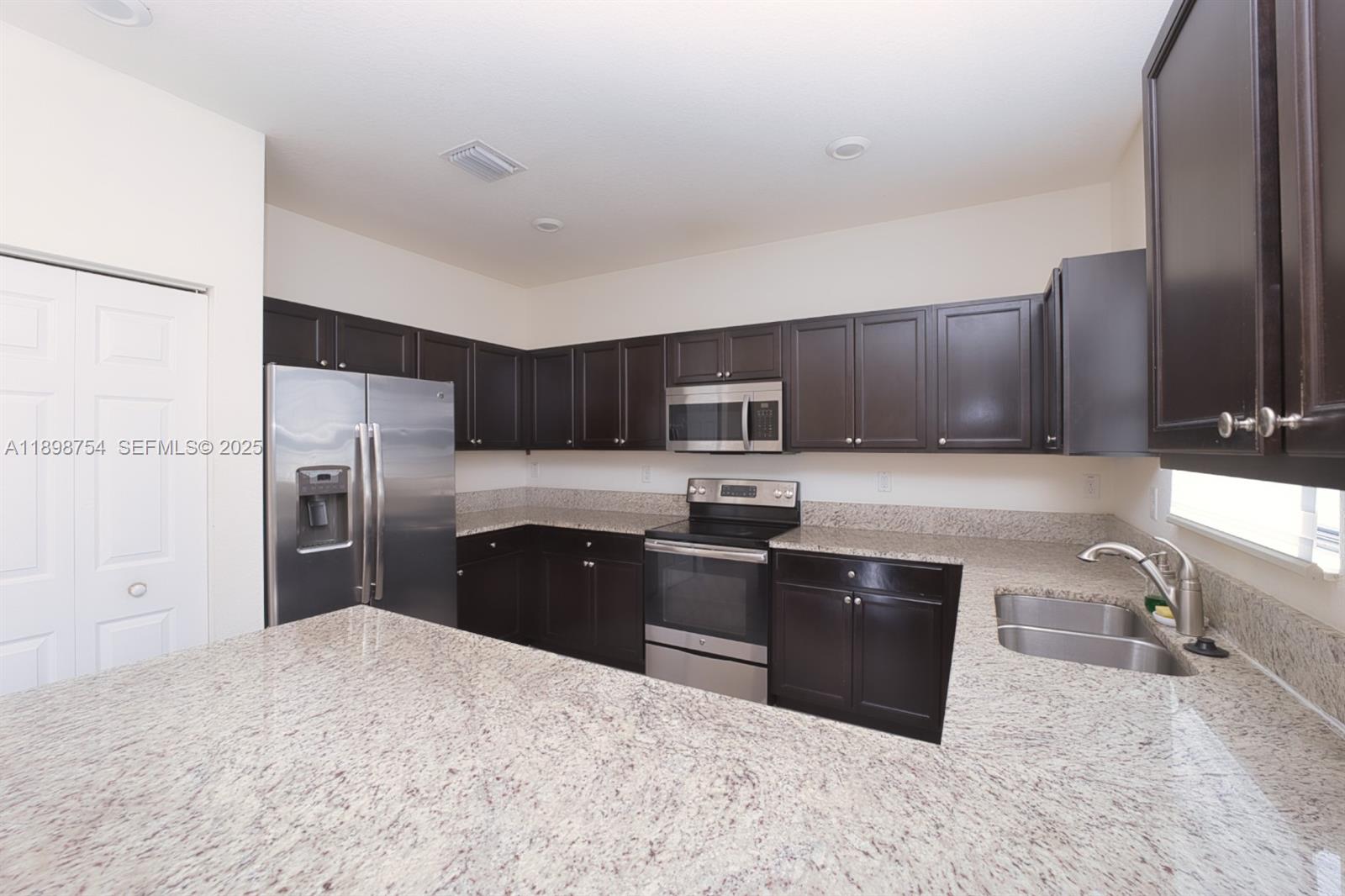 3412 West 103rd Terrace Hialeah, FL 33018 - Photo 10 of 44 a kitchen with stainless steel appliances granite countertop a refrigerator stove microwave and sink
