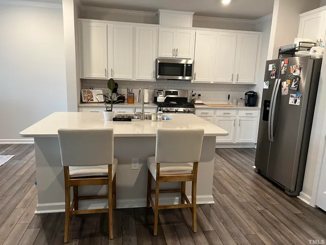a kitchen with a dining table chairs refrigerator and microwave